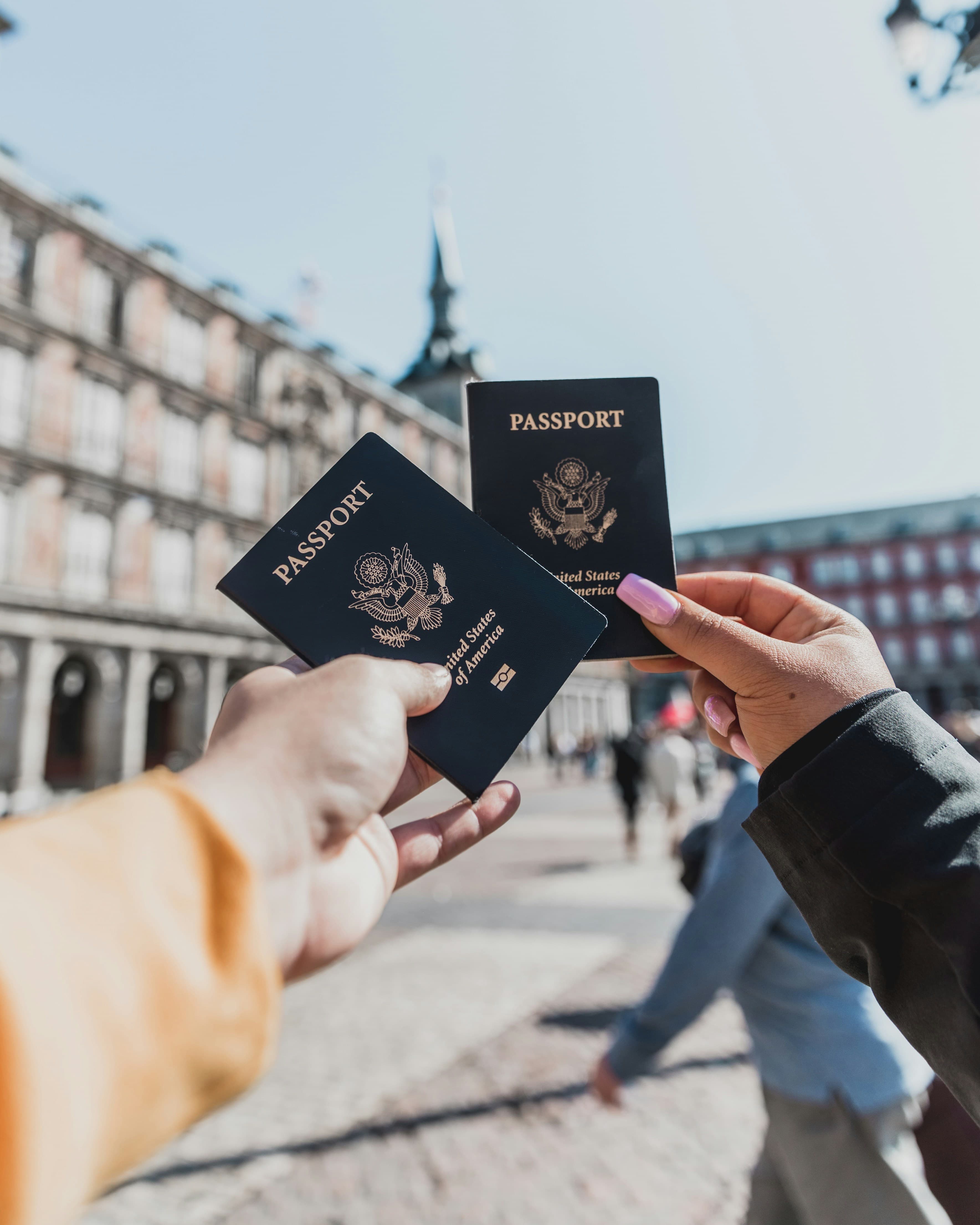 Two travellers holding US passports in a historic European city square